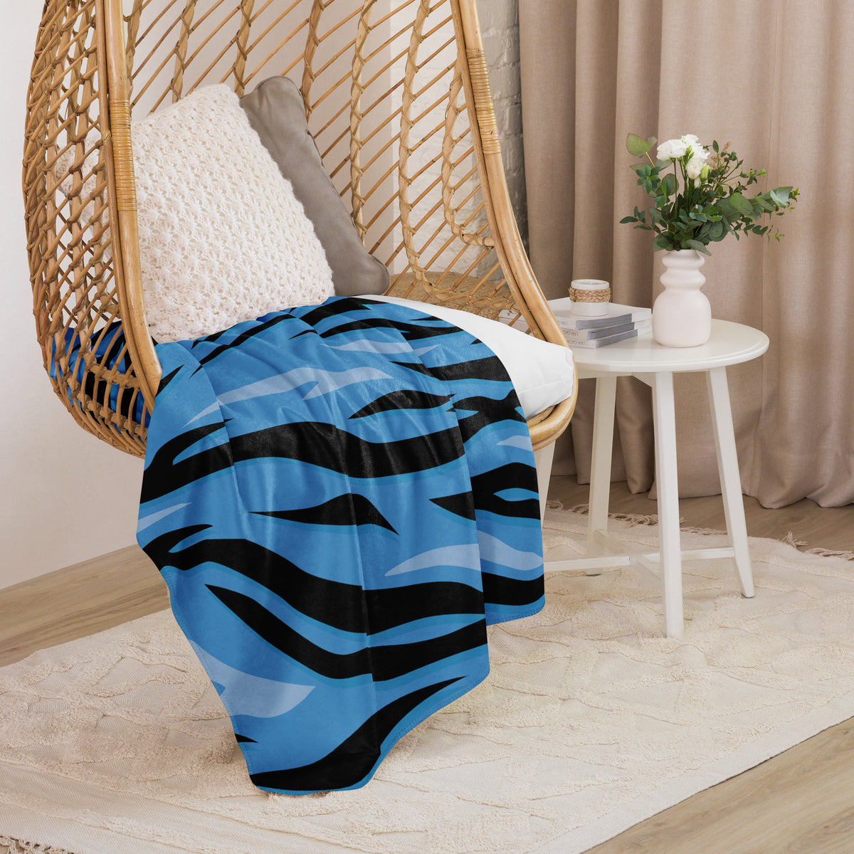 A vibrant blue and black zebra-striped woven throw blanket draped over a wicker hanging chair