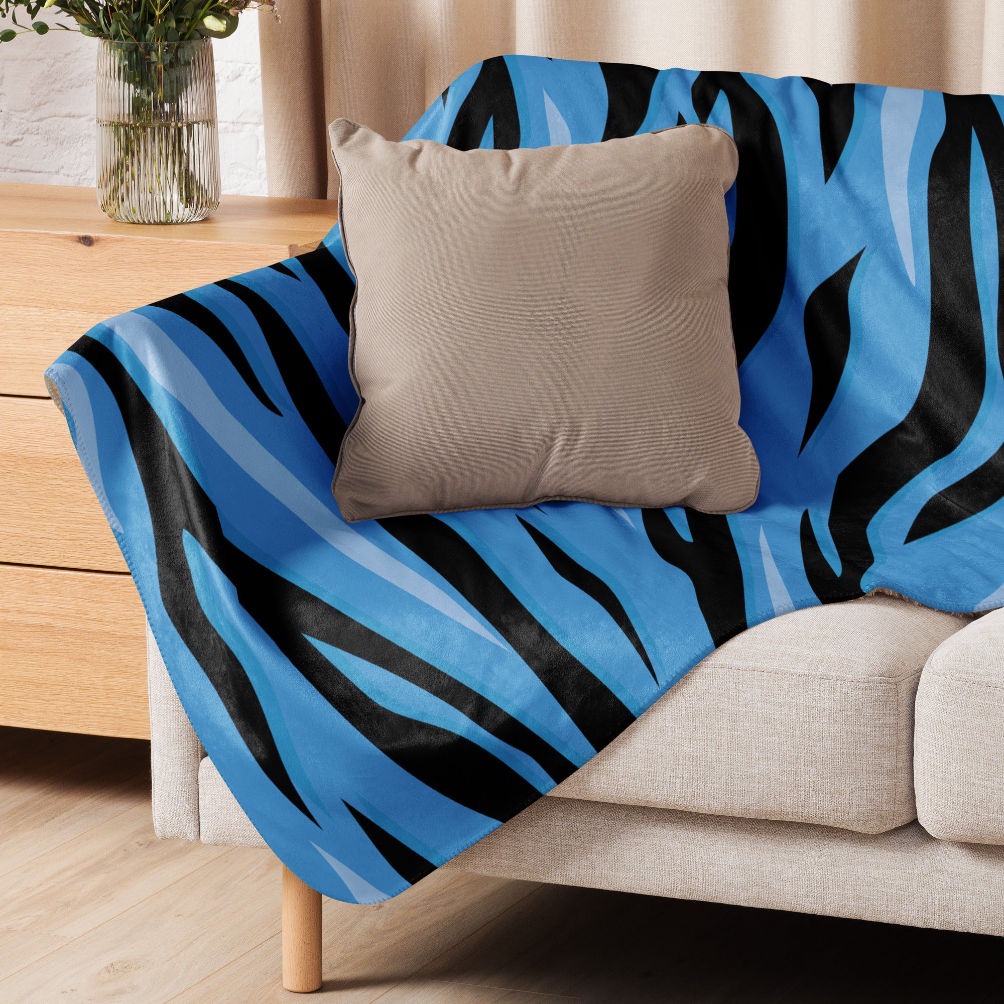Blue tiger blanket with blue and black zebra stripes draped over a beige sofa for cozy home use