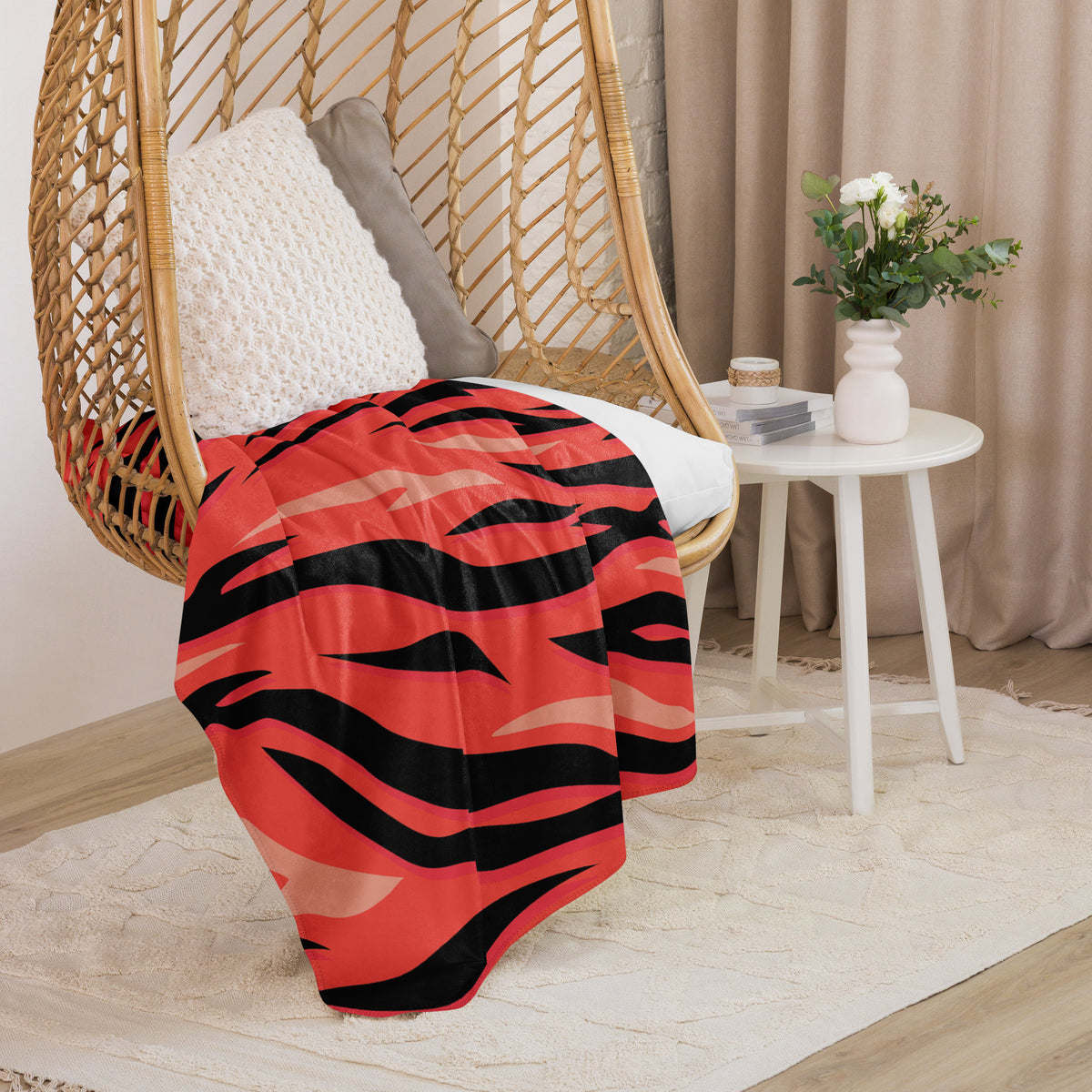 A vibrant red and black tiger stripe throw blanket draped over a wicker hanging chair for cozy decor