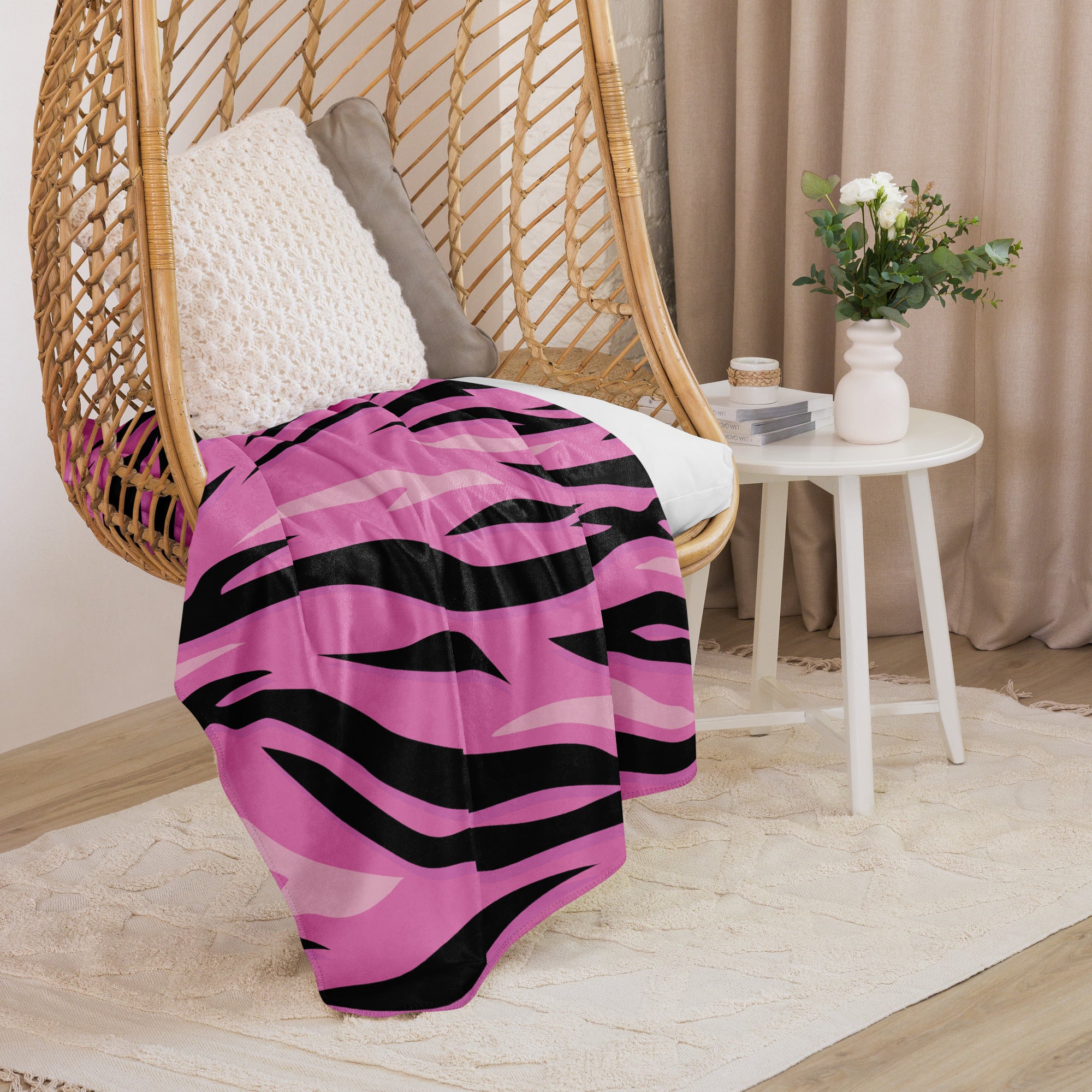 A vibrant pink and black zebra-striped throw blanket draped over a wicker hanging chair for cozy decor