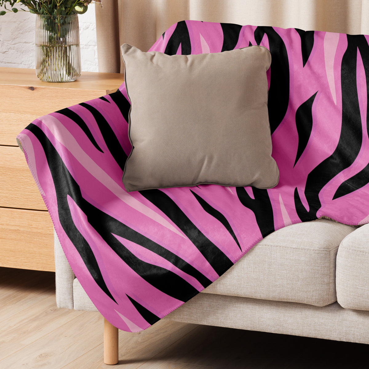 A vibrant pink and black zebra-striped pink tiger blanket draped over a beige sofa