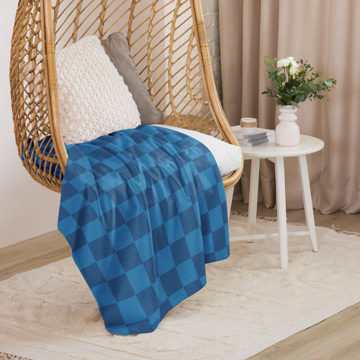 Blue checkered cotton blanket draped over a wicker hanging chair perfect for cozy indoor or outdoor use