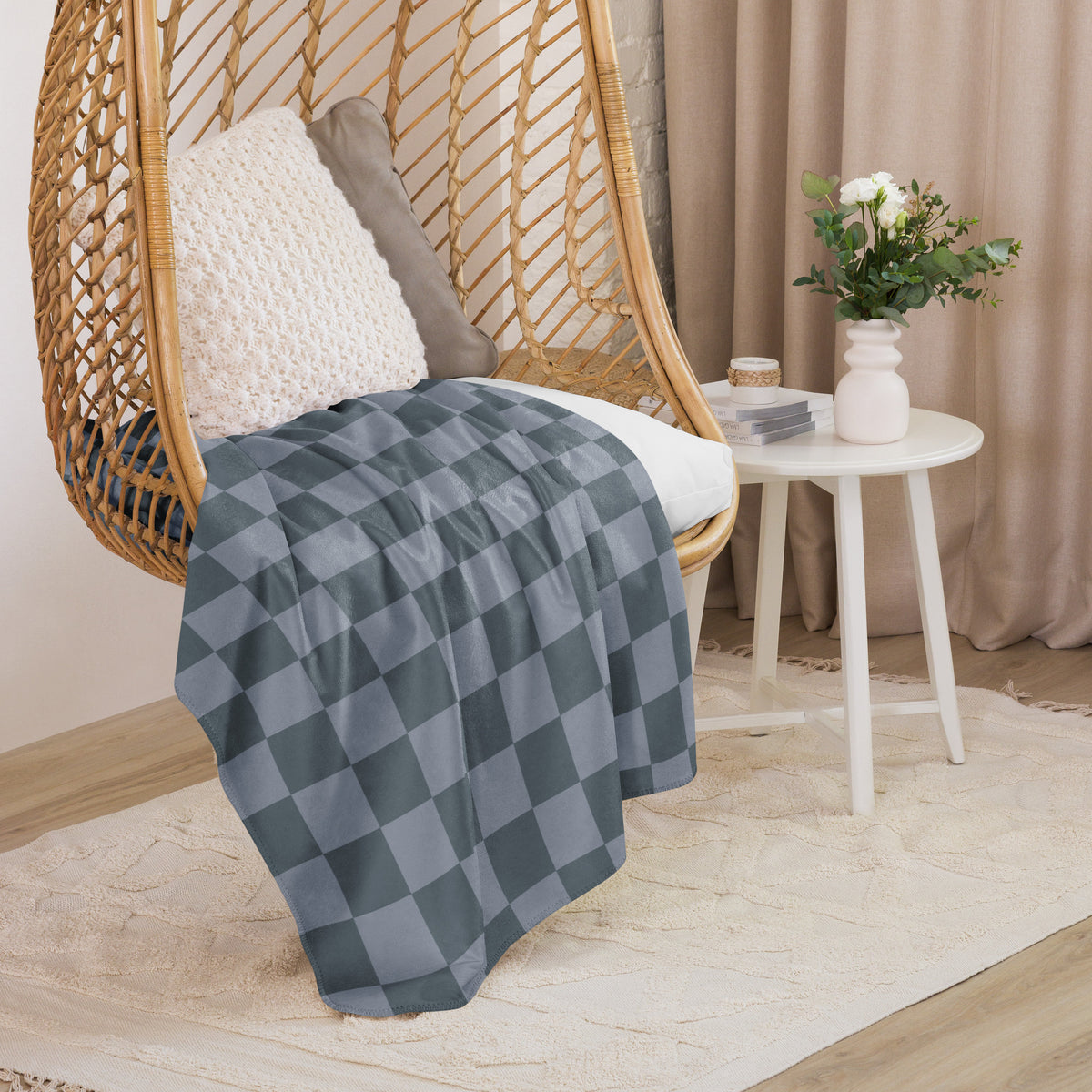 A soft gray and black checkered throw blanket draped over a wicker hanging chair for cozy indoor use
