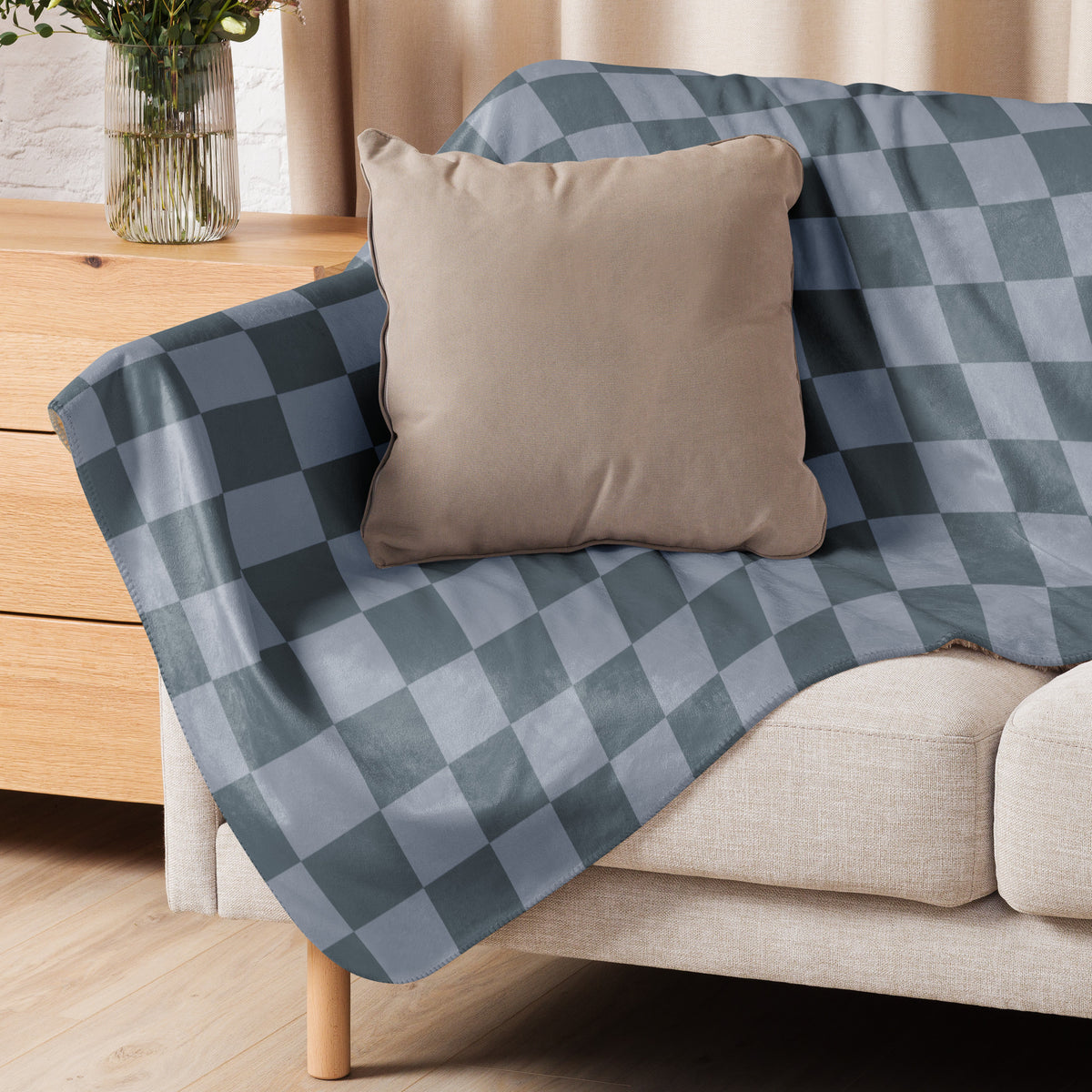 Grey checkered blanket in blue and gray draped over a beige sofa showing soft woven fabric and cozy texture