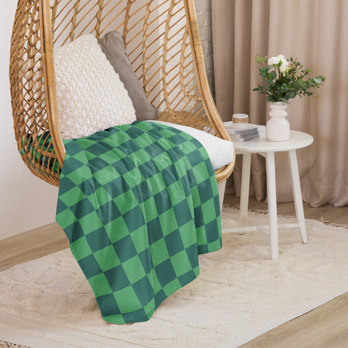 Green checkered blanket with dark green squares draped over a wicker hanging chair for cozy use
