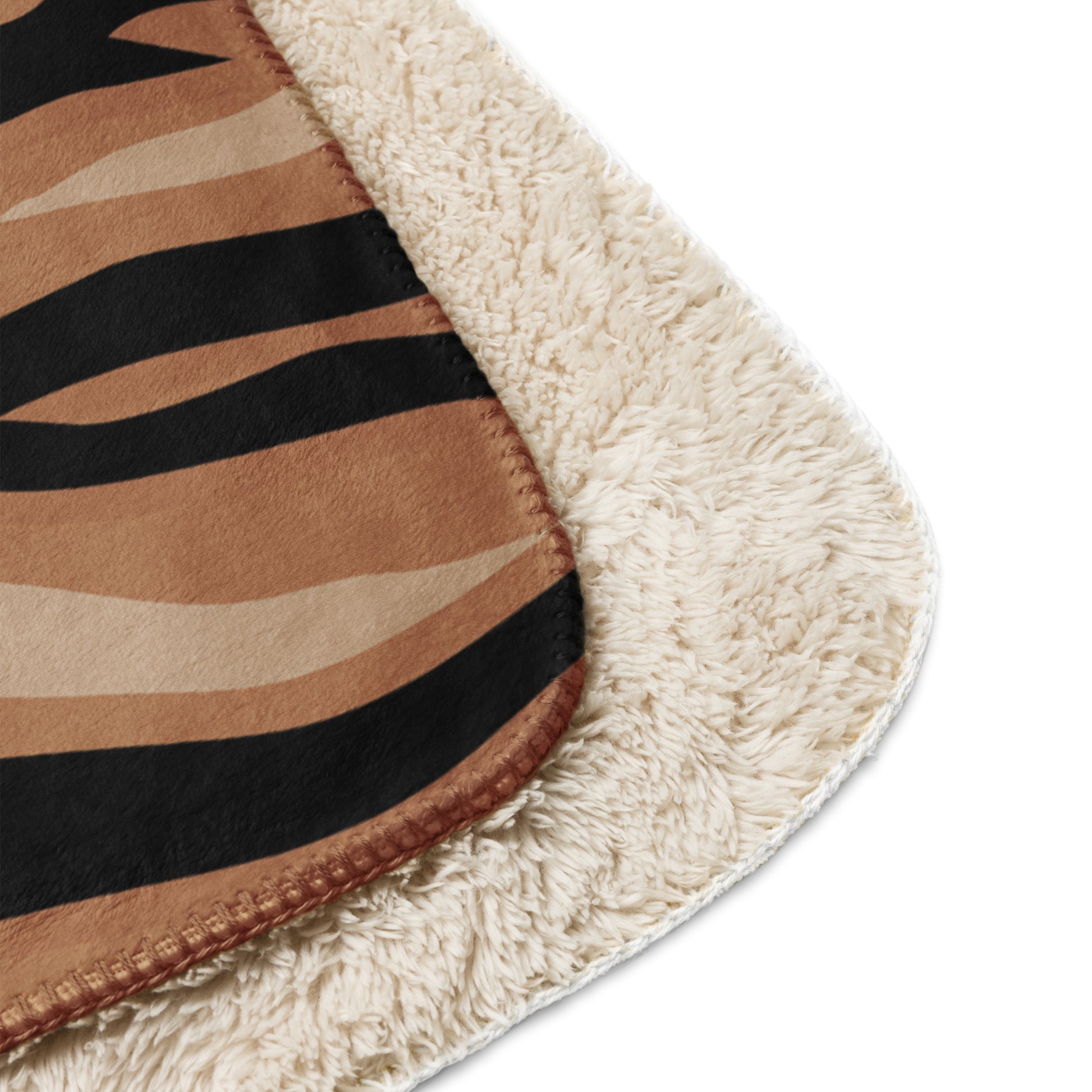 A cozy cream-colored sherpa brown tiger blanket with bold black and tan zebra stripe pattern on the outer surface