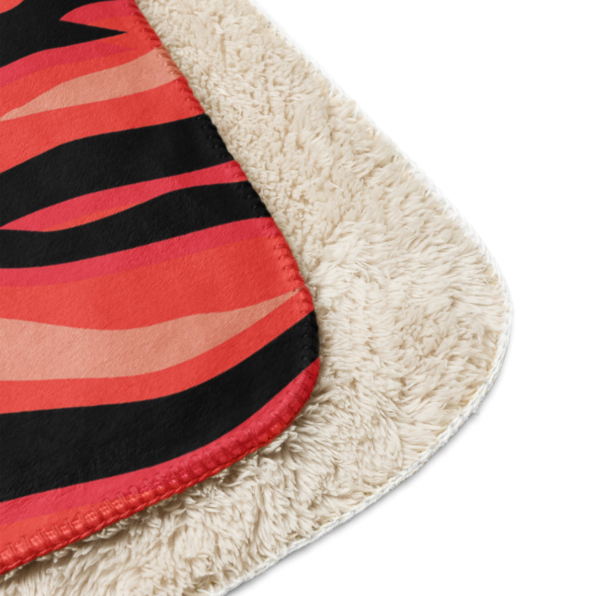 A cozy cream sherpa red tiger blanket with a bold red and black zebra-striped outer surface