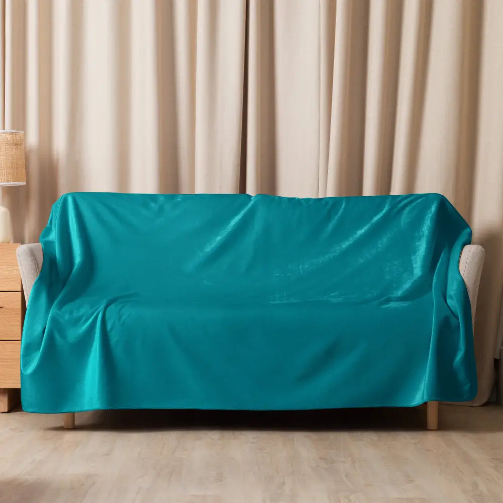 Teal sherpa throw blanket draped over teal velvet sofa cover showing soft textured cozy fabric and rich color