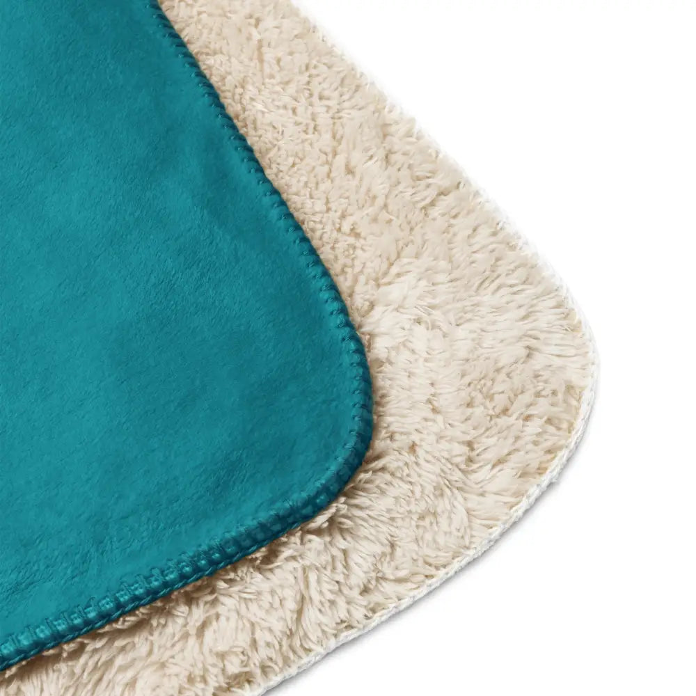 Teal sherpa throw blanket with a soft fuzzy cream-colored border made of plush material for cozy warmth