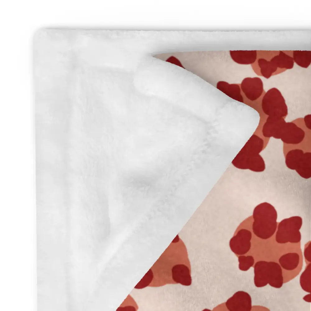 Cozy cream-colored throw blanket with red paw prints on one side and soft white plush lining