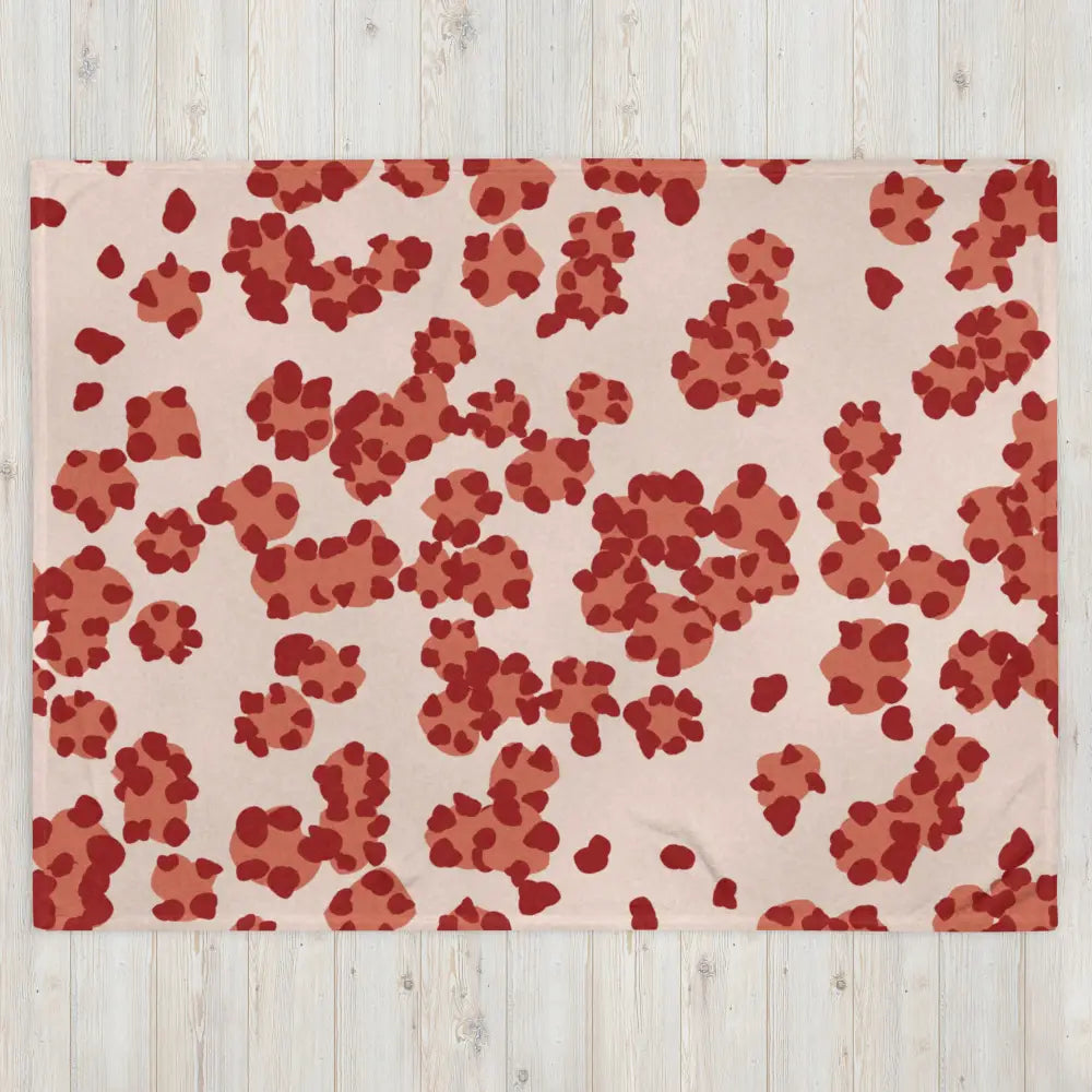 A soft blush pink fleece throw blanket with rust and deep red paw prints scattered in a playful pattern