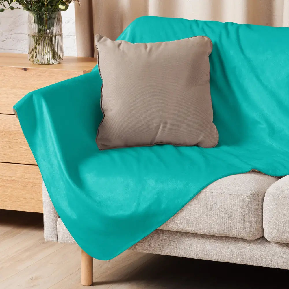 Teal-colored plush sherpa blanket draped over a sofa showcasing soft cozy material for home comfort