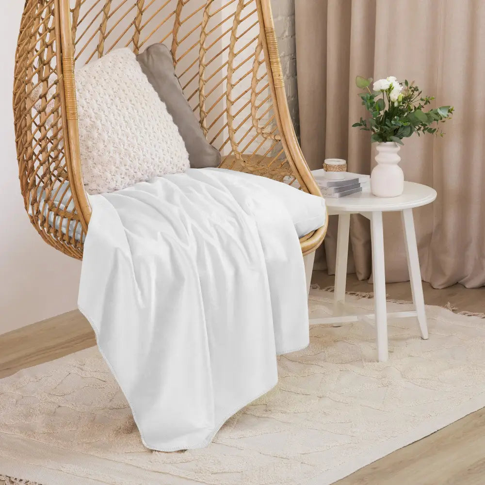 White sherpa blanket soft white throw draped over woven rattan hanging chair for cozy comfort