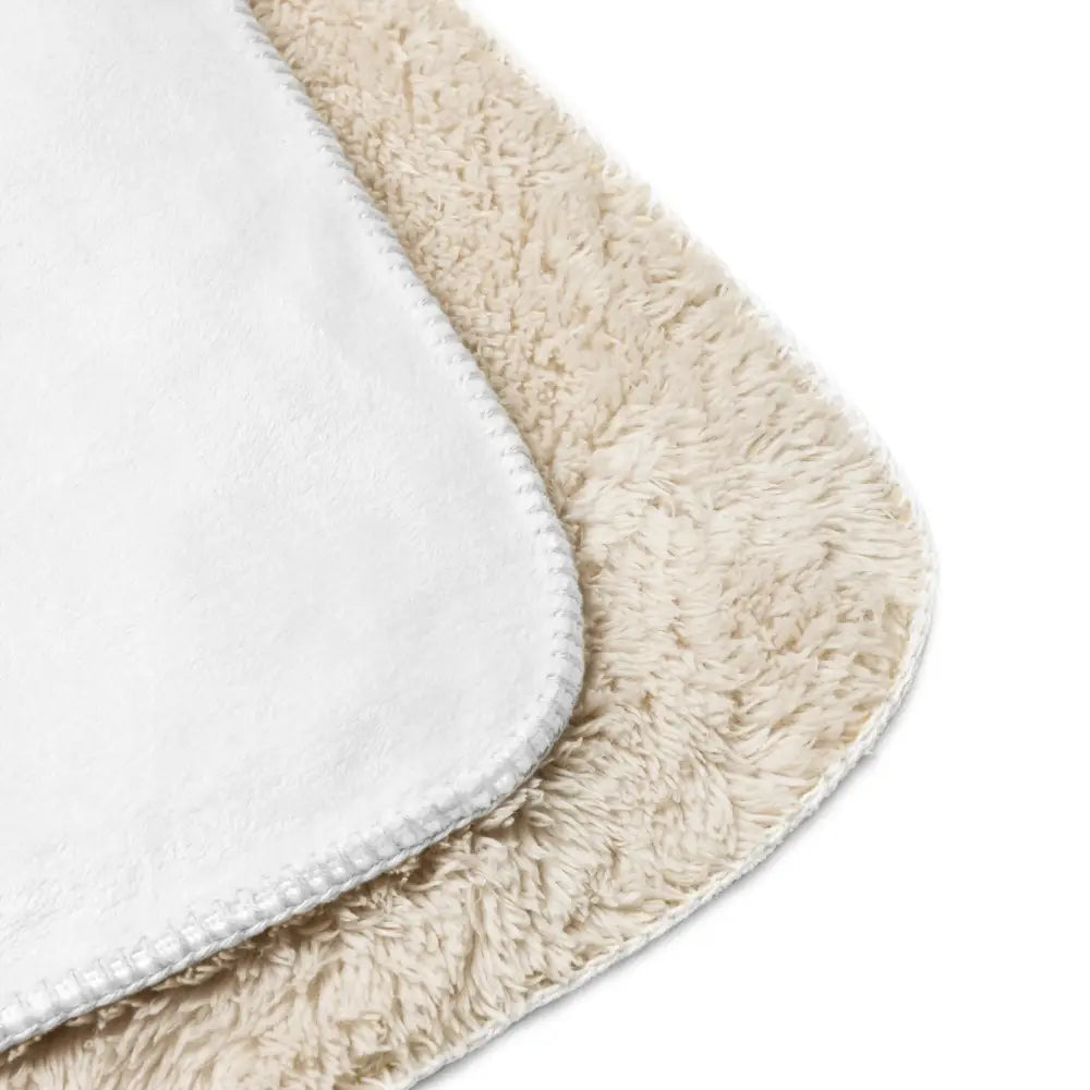 Cream-colored plush bath mat with soft fluffy texture and white stitched edges complementing white sherpa blanket