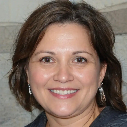 A woman with shoulder-length brown hair and a warm smile, wearing dangling silver earrings.