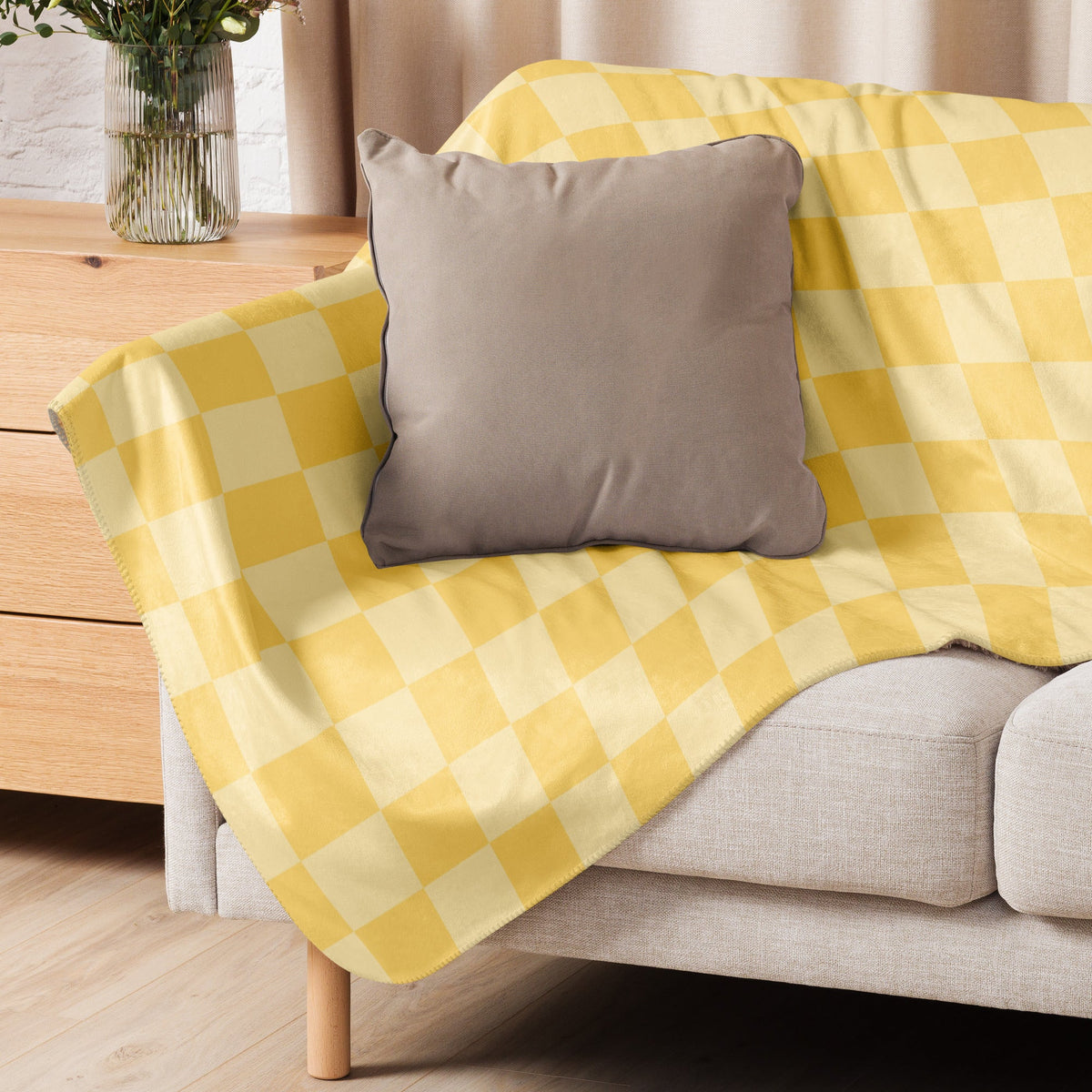 Yellow checkered blanket in yellow and cream draped over a sofa made of soft woven material