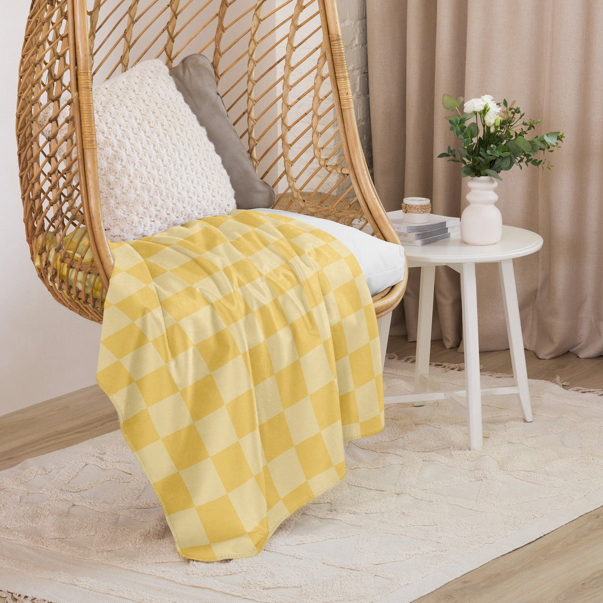 Yellow and white checkered cotton blanket draped over a wicker hanging chair for cozy outdoor use