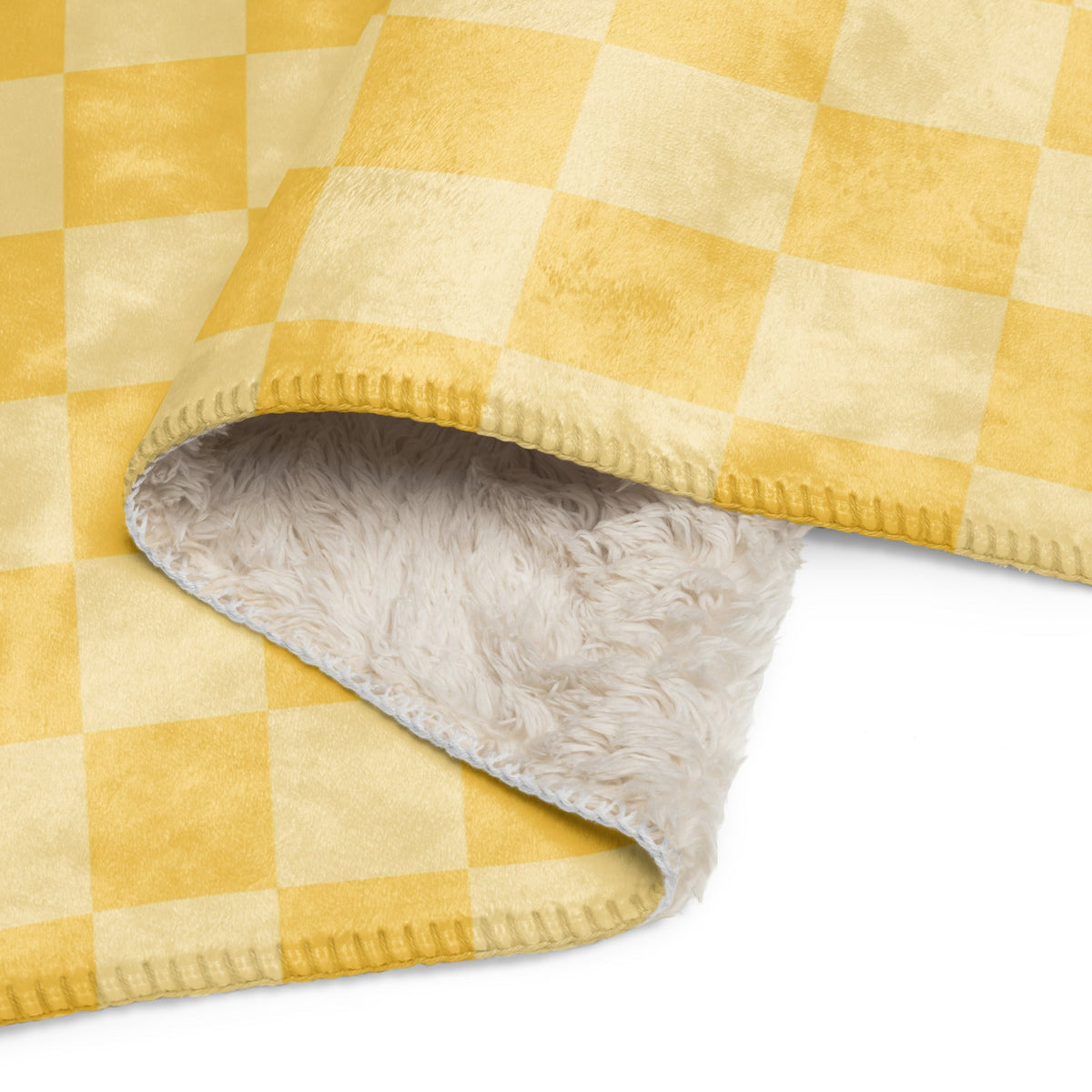 A cozy yellow and cream checkered blanket with a plush fluffy white interior lining for warmth and comfort